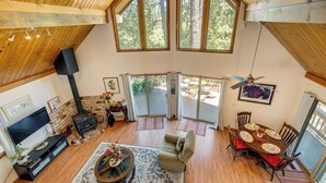 A spacious living area with a fireplace, a TV, a dining table with chairs, and a ceiling fan. - Groveland Vacation Rental ~ 26 Miles to Yosemite! (Groveland)