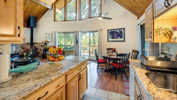 A spacious kitchen with wooden cabinets, a granite countertop, and a dining area with a table and chairs. - Groveland Vacation Rental ~ 26 Miles to Yosemite! (Groveland)
