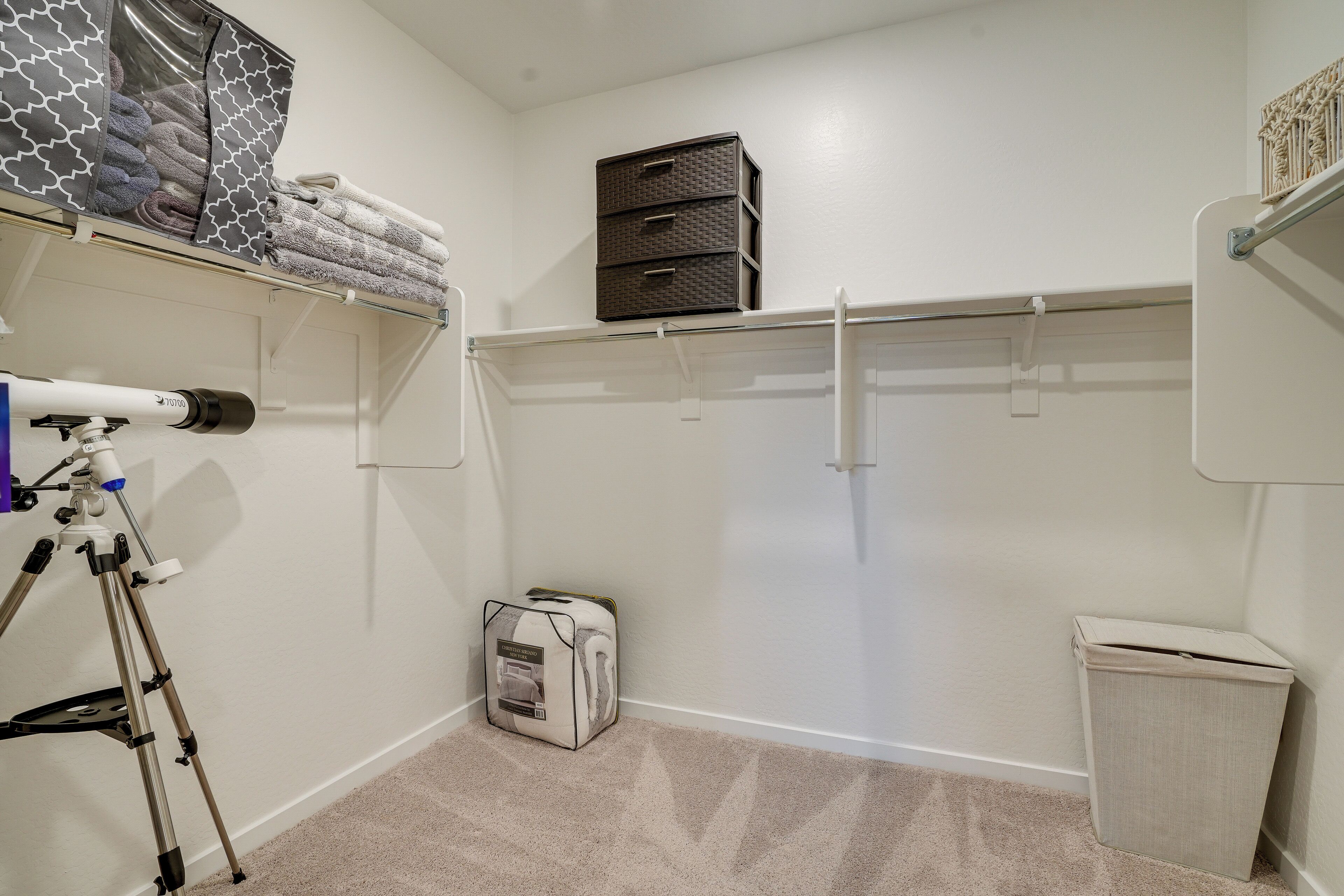 A small, neatly organized room with a closet, a storage box, and a trash bin.