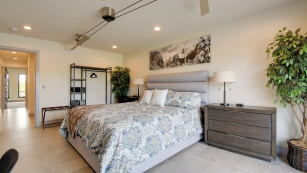 A bedroom with a bed, bedside tables, a dresser, a ceiling fan, a wall-mounted TV, and a large potted plant. - Game Room! Luxury Group Getaway in Fountain Hills (Fountain Hills)