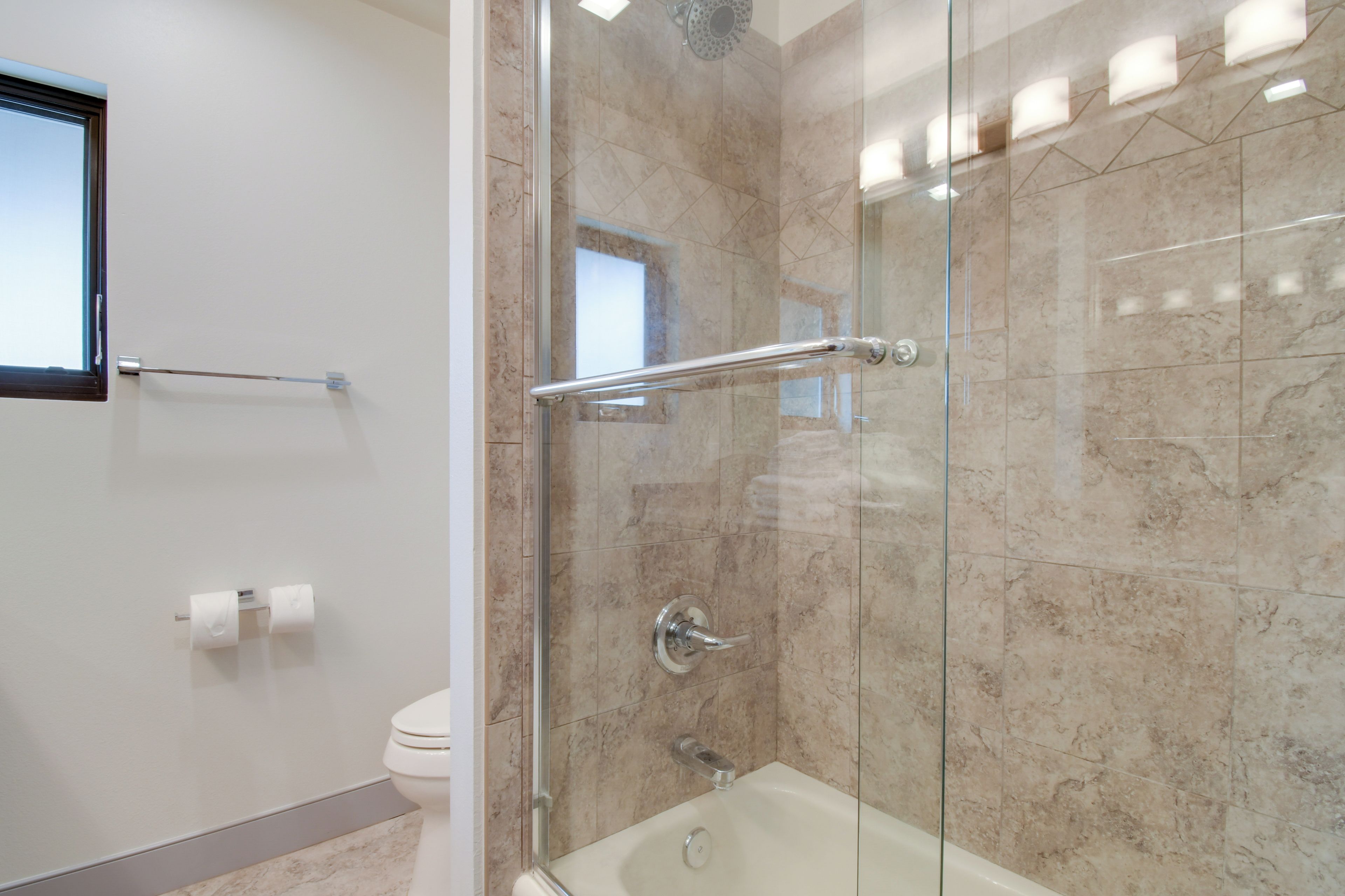 A modern bathroom with a glass-enclosed shower, a toilet, and a towel rack.