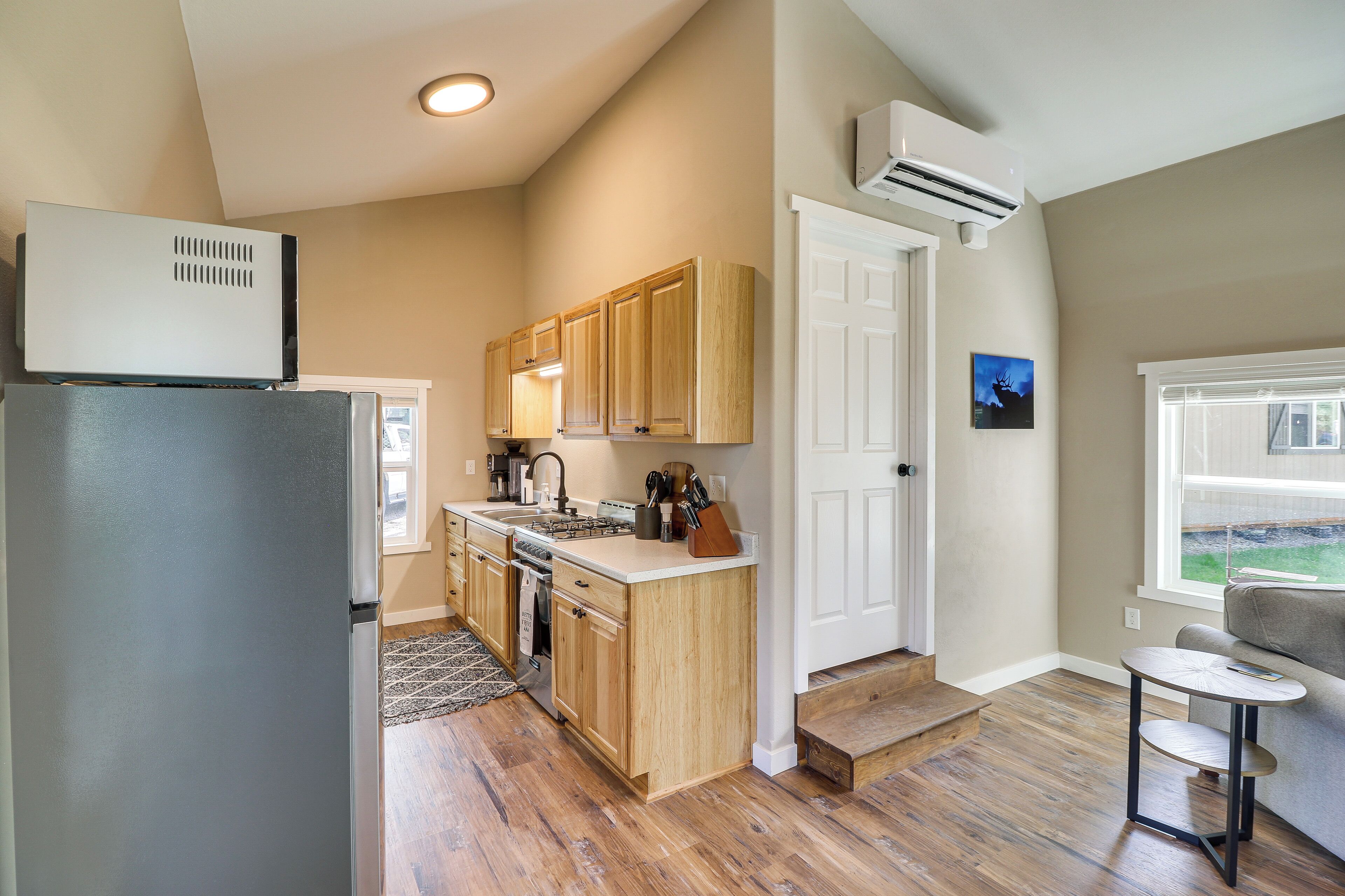 A kitchen with wooden cabinets, a refrigerator, and a window with a view.