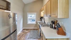 A kitchen with a stainless steel refrigerator, wooden cabinets, a gas stove, and a window providing a view of the outside.