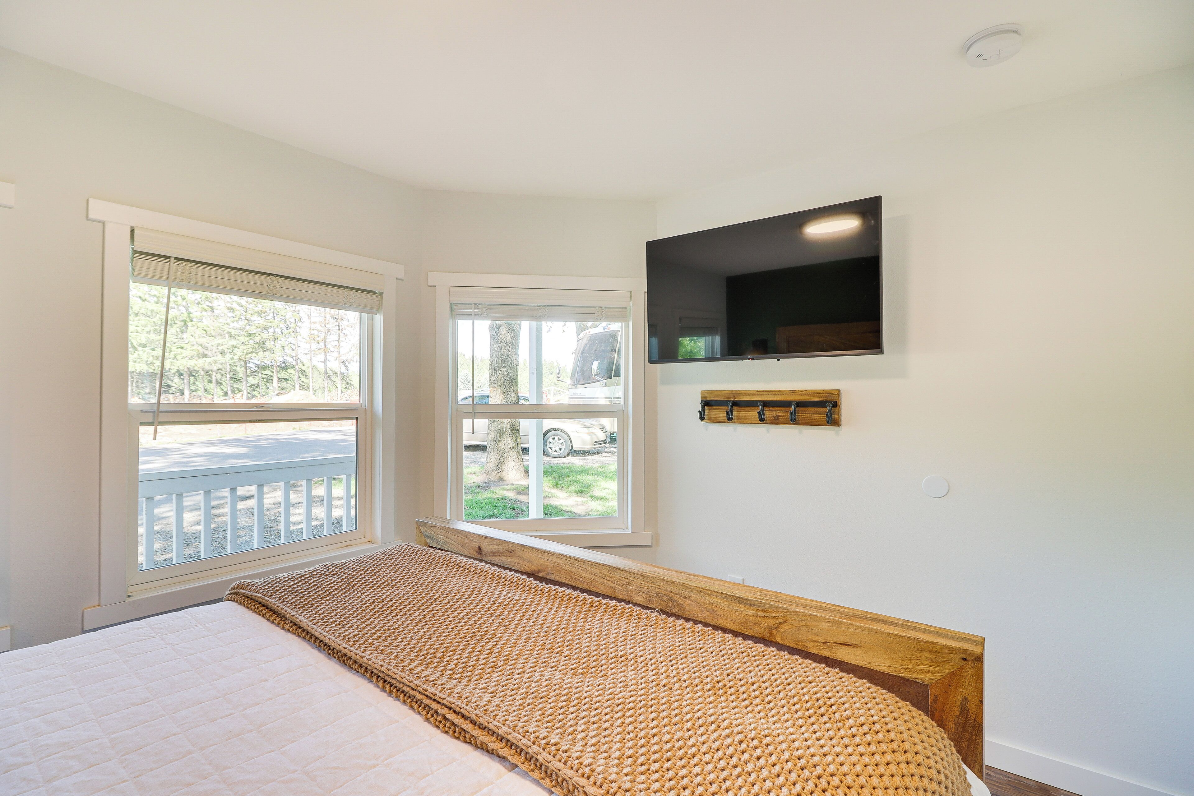 A bedroom with a bed, a window, a television, and a small shelf.