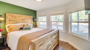 A bedroom with a wooden headboard, a large window, and a view of the outdoors.