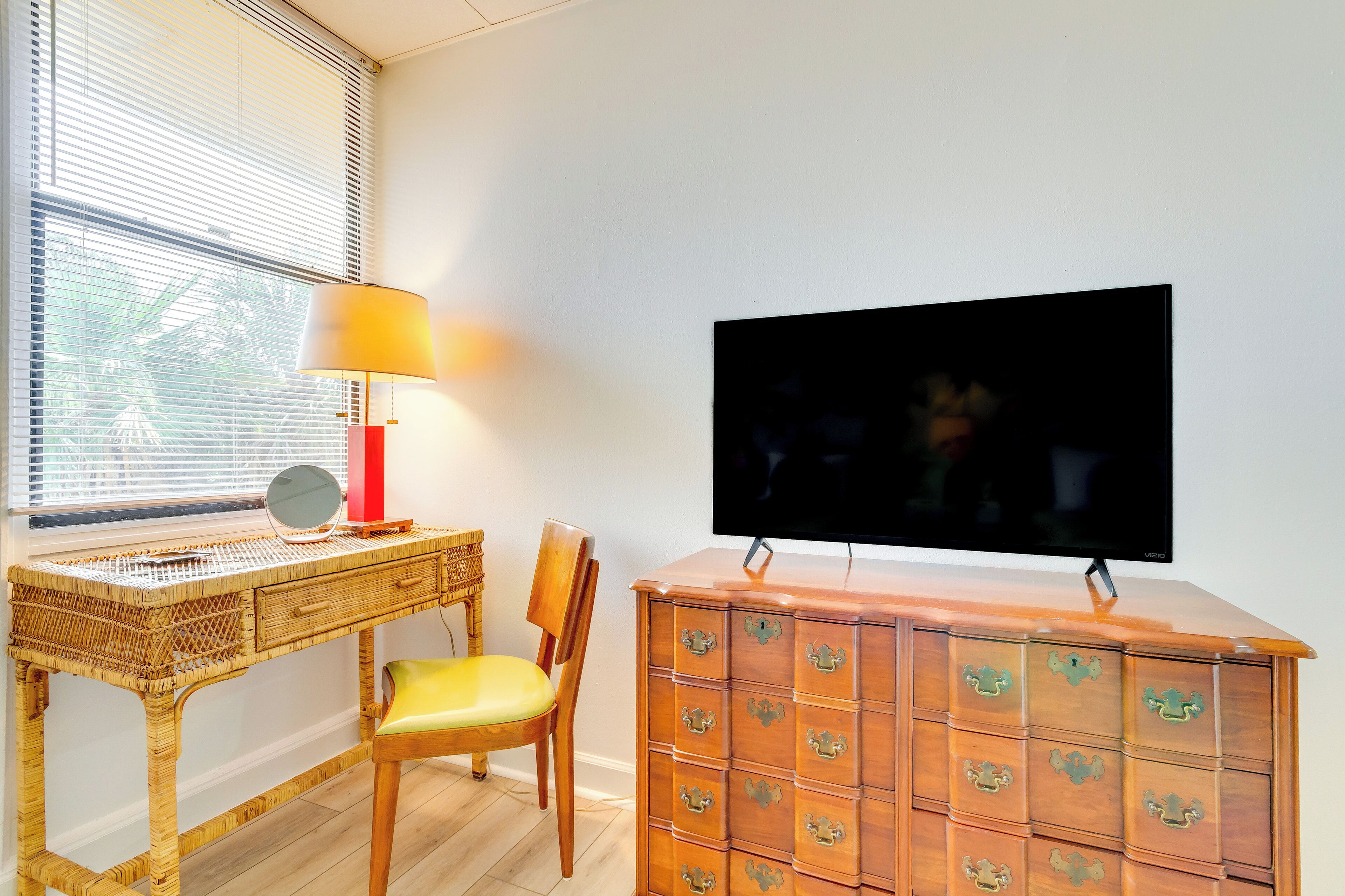 Una habitación con un escritorio de madera, una silla, un televisor y un mueble de madera con varios cajones.