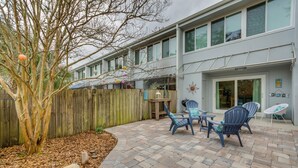 Un patio con mobiliario exterior, una valla de madera y un edificio con un letrero que dice 'Beach'.