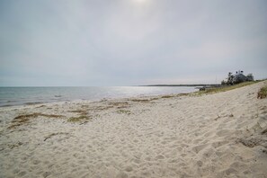 A sandy beach with a house on a hill overlooking the sea.