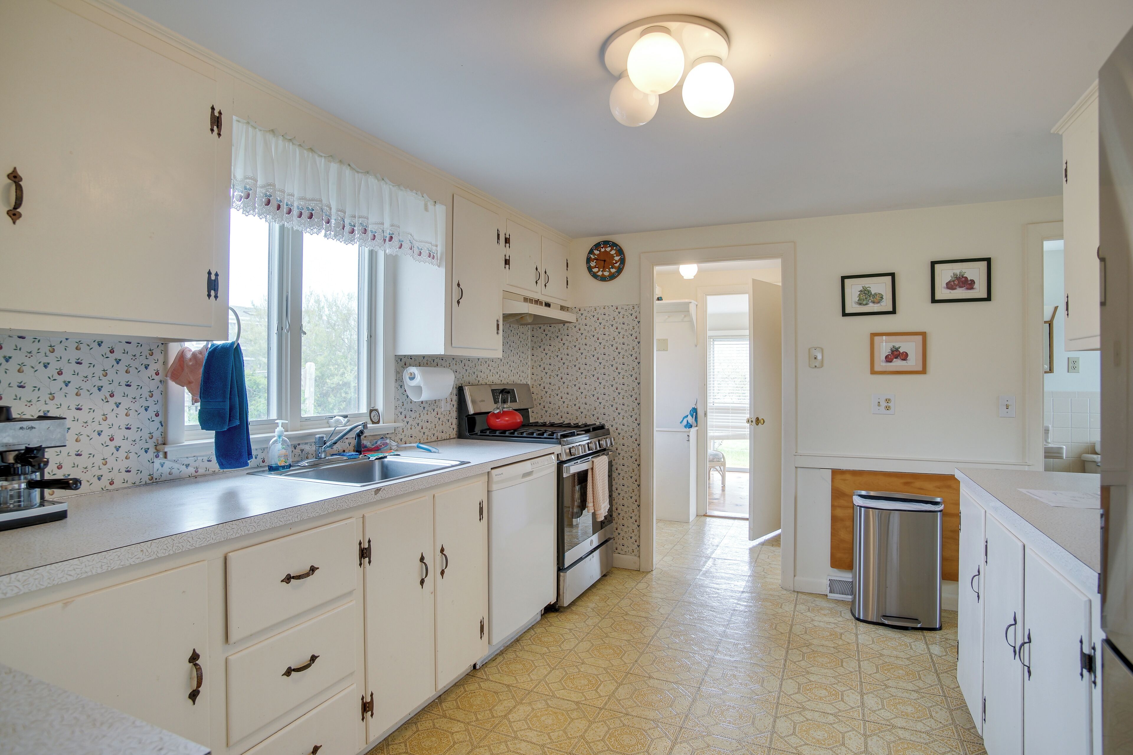 A kitchen with white cabinets, a stove, and a sink.