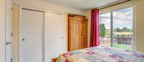 A bedroom with a large bed, a wardrobe, and a sliding glass door to a balcony.