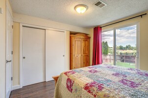 Un dormitorio con una cama grande, un armario y una puerta corrediza de cristal a un balcón.