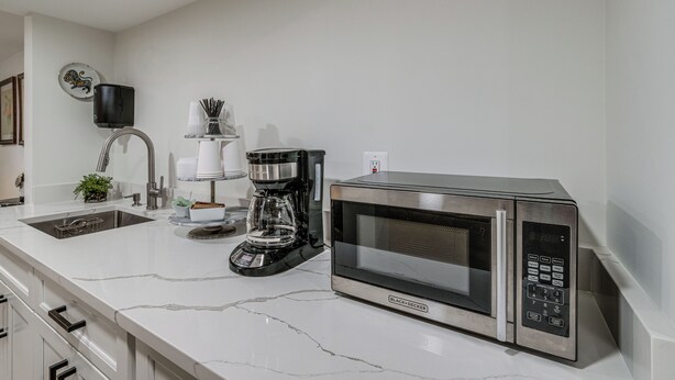 A modern kitchen with a stainless steel microwave, a coffee maker, and a sink.
