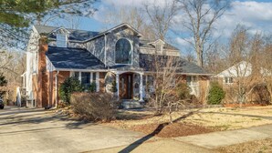 A two-story house with a stone facade, a prominent front entrance, and a well-maintained lawn.