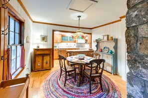 Une cuisine chaleureuse avec des meubles de rangement en bois, une table à manger avec des chaises et un tapis aux couleurs vives.