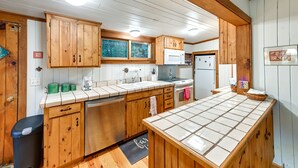 A kitchen with wooden cabinets, a microwave, a sink, and a refrigerator. - Highlands Vacation Rental - Walk to Mirror Lake! (Highlands)