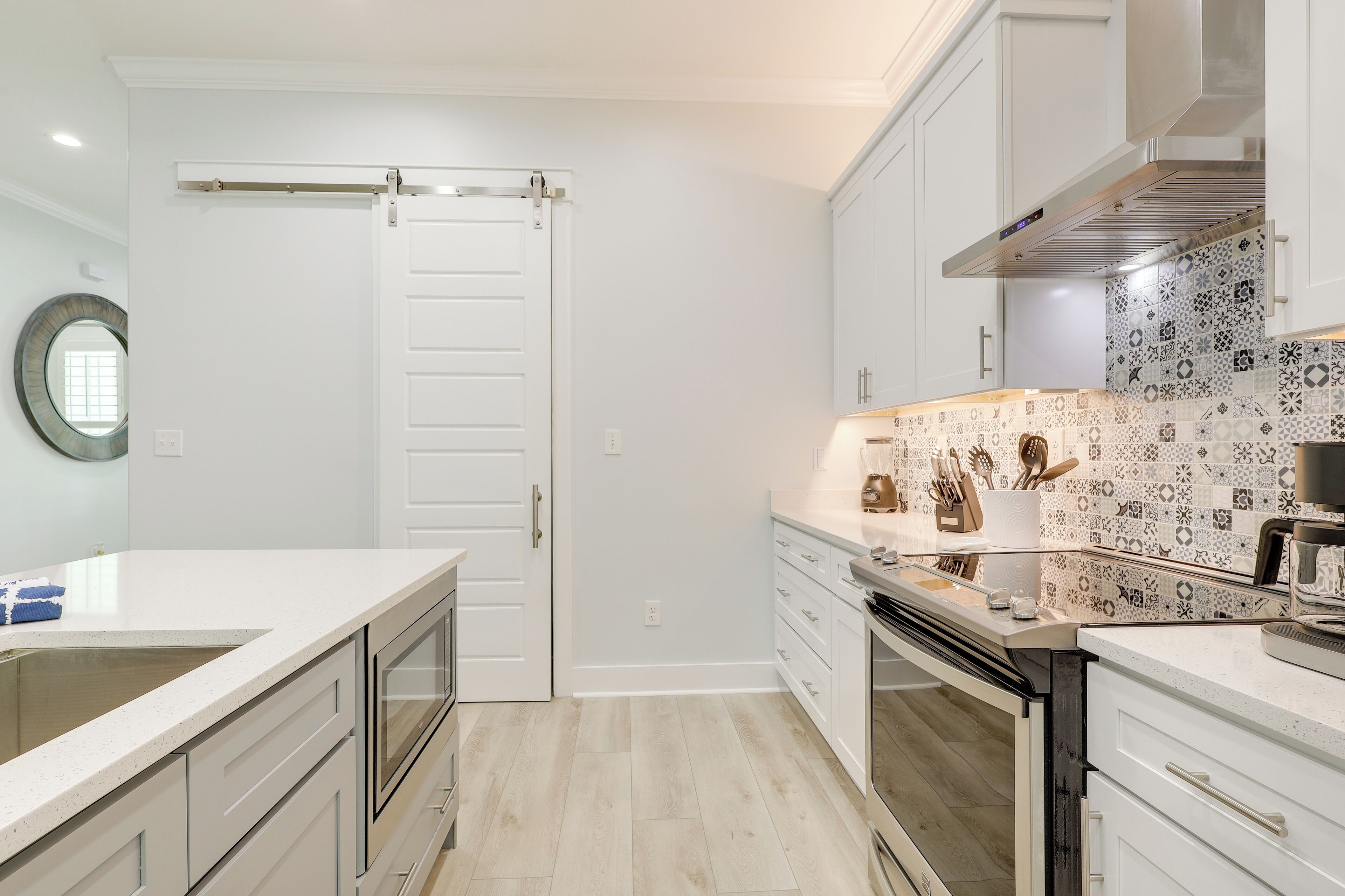 A modern kitchen with white cabinetry, a large island, and a patterned backsplash.