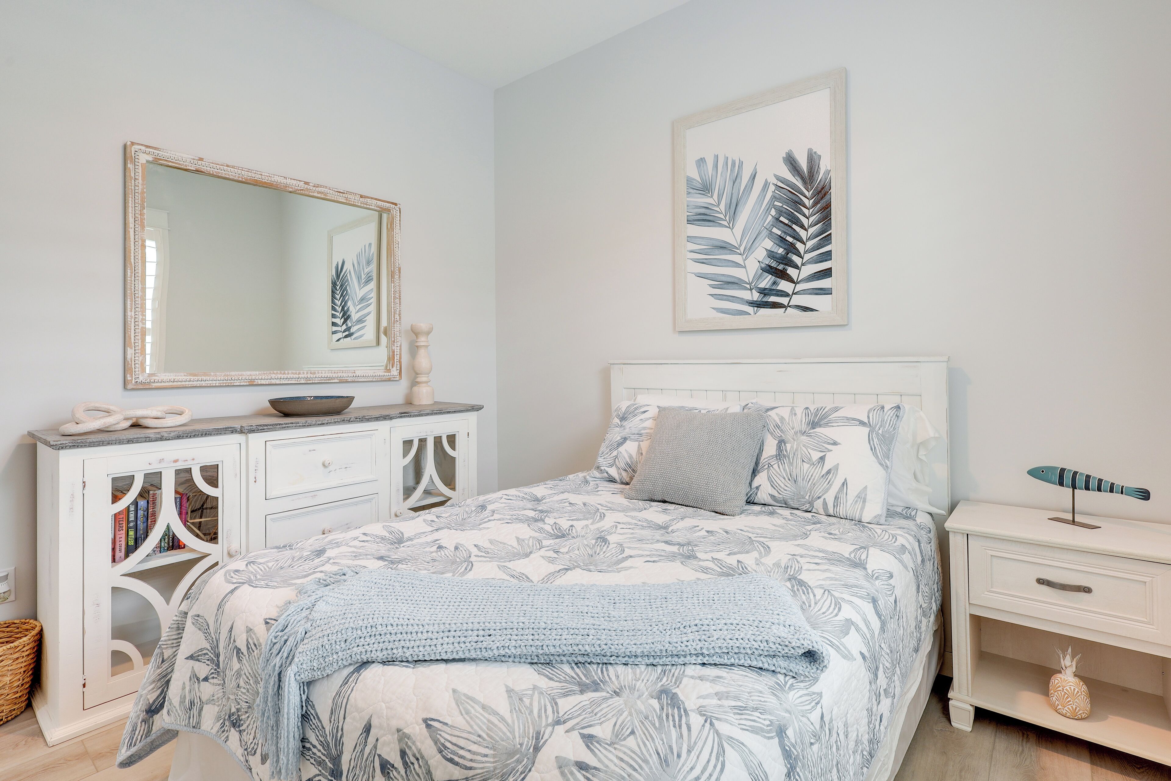 A bedroom with a bed, a dresser, a nightstand, and a mirror.