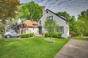Two-story house with a gable roof and chimney, set amidst a well-manicured lawn and a small tree.