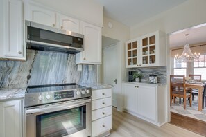 A kitchen with white cabinetry, a stainless steel range, and a marble countertop.