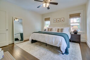 Relax in this serene bedroom with a large bed, nightstands, and a ceiling fan above.