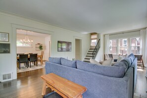 A spacious living room with a grey sofa, wooden bench, and a staircase leading to an upper floor. - Pet-friendly Cincinnati Retreat w/ Hot Tub (Cincinnati)