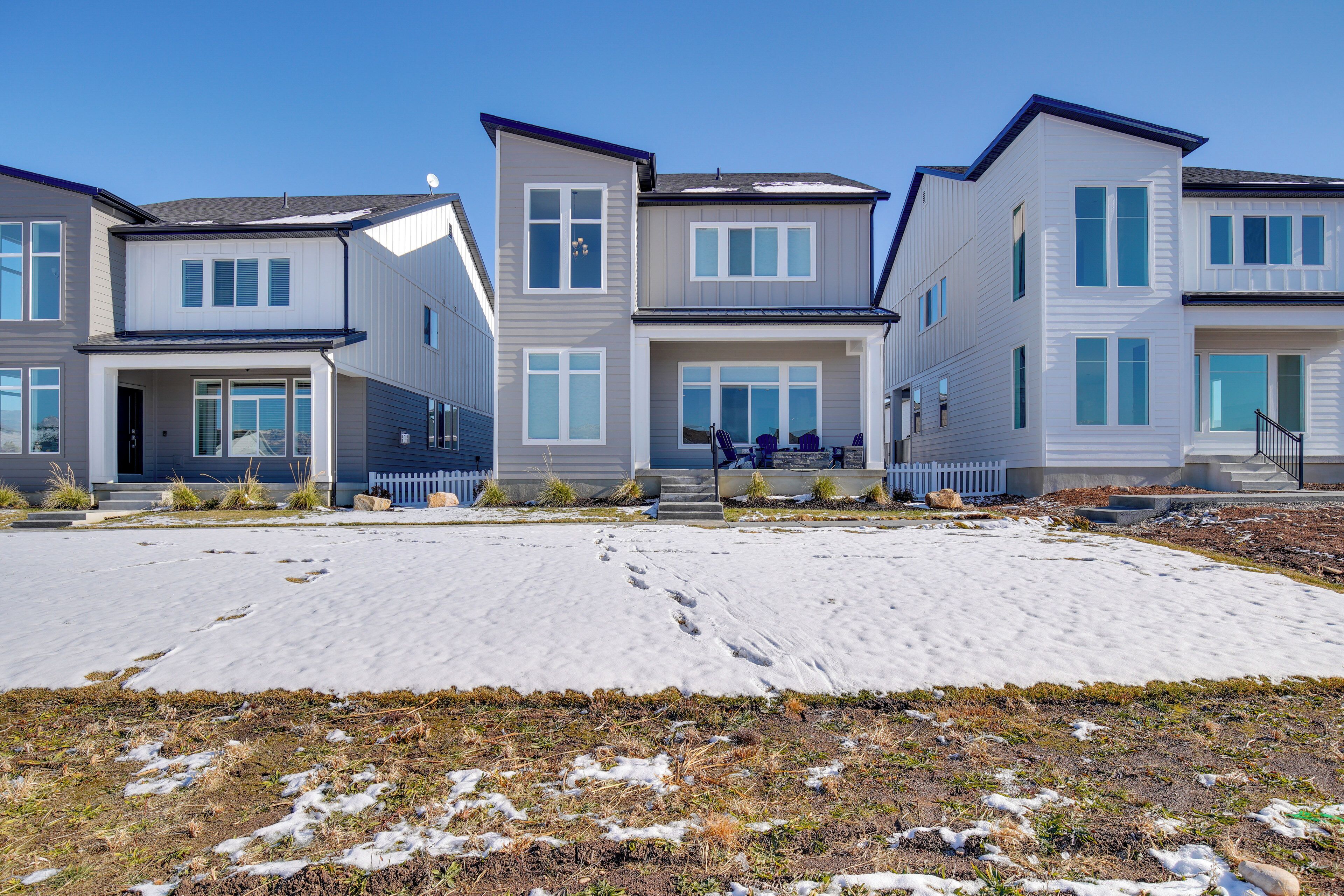 A row of modern townhouses with a covered front porch and a small garden area.