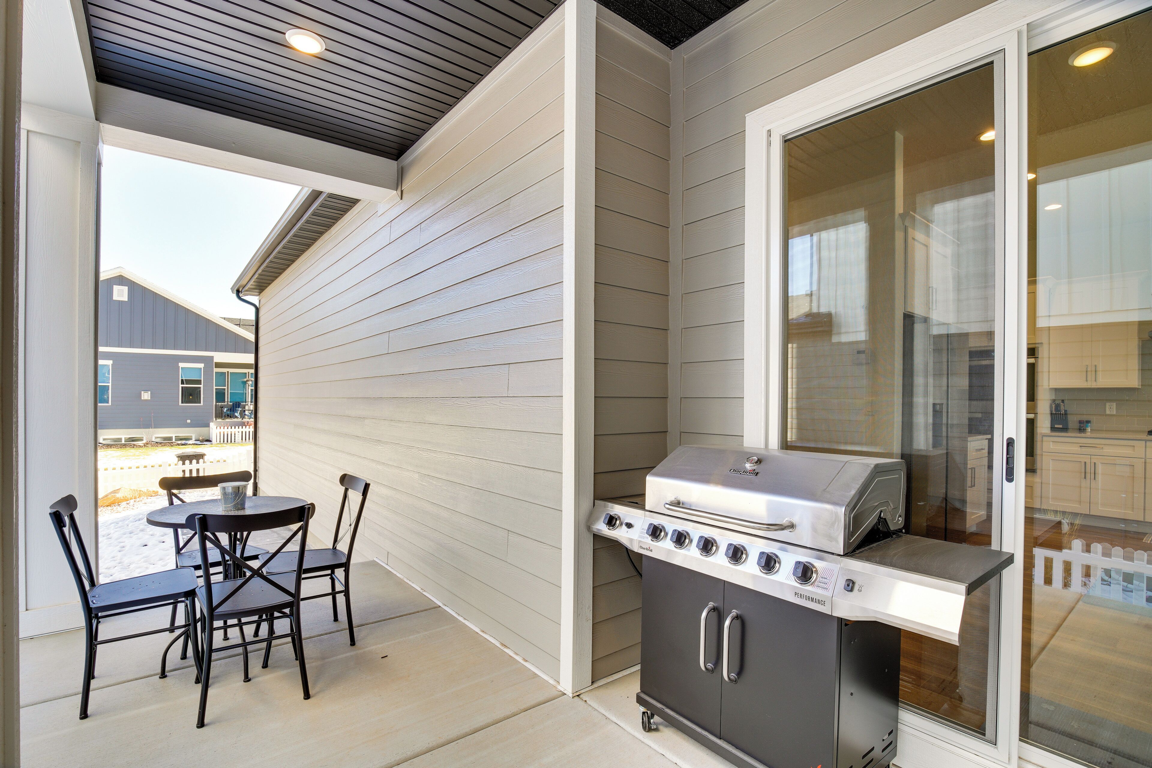 A covered patio with a grill, a table, and four chairs.