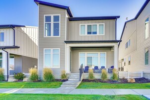 A two-story townhouse with a front porch, a satellite dish, and a small garden with plants and a white picket fence.