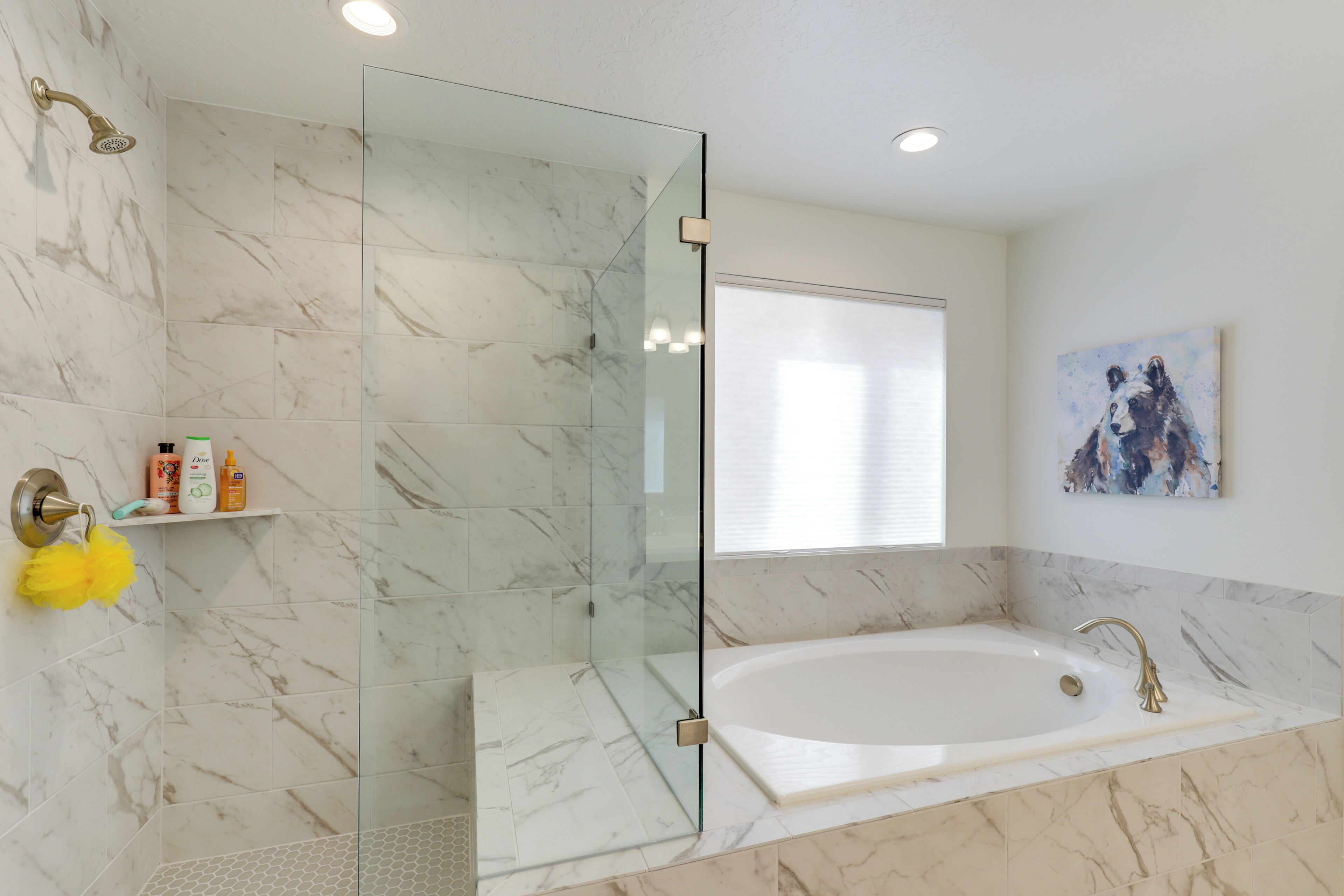 A modern bathroom with a glass-enclosed shower, a large bathtub, and marble flooring.