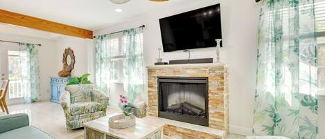 A living room with a fireplace, a television, and a ceiling fan.