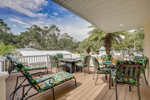 Relax on the covered patio with a table and chairs featuring a tropical leaf pattern.