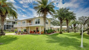 A two-story house with a covered porch, surrounded by a well-maintained lawn and palm trees. - St Augustine Home Near Vilano Beach: Pets Welcome! (St. Augustine)