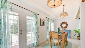 A bright dining area with a wooden table and chairs, a blue cabinet, and a large mirror on the wall. - St Augustine Home Near Vilano Beach: Pets Welcome! (St. Augustine)