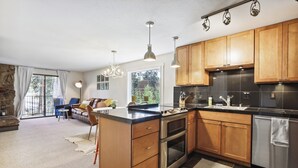A modern kitchen with wooden cabinets, stainless steel appliances, and pendant lighting.