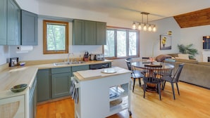 A modern kitchen with a central island, wooden flooring, and a dining area with a round table and chairs.