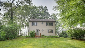 A two-story house with a front porch, surrounded by a well-maintained lawn and trees.