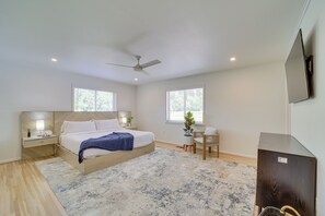 A modern bedroom with a bed, bedside tables, a desk, a chair, and a television. - Well-appointed Tulsa Home w/ Fire Pit & Patio! (Tulsa)