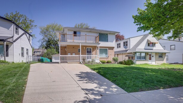 A two-story residential building with a front porch, a visible satellite dish, and a well-maintained lawn. - Comfortable Milwaukee Abode ~ 10 Mi to Downtown! (Milwaukee)