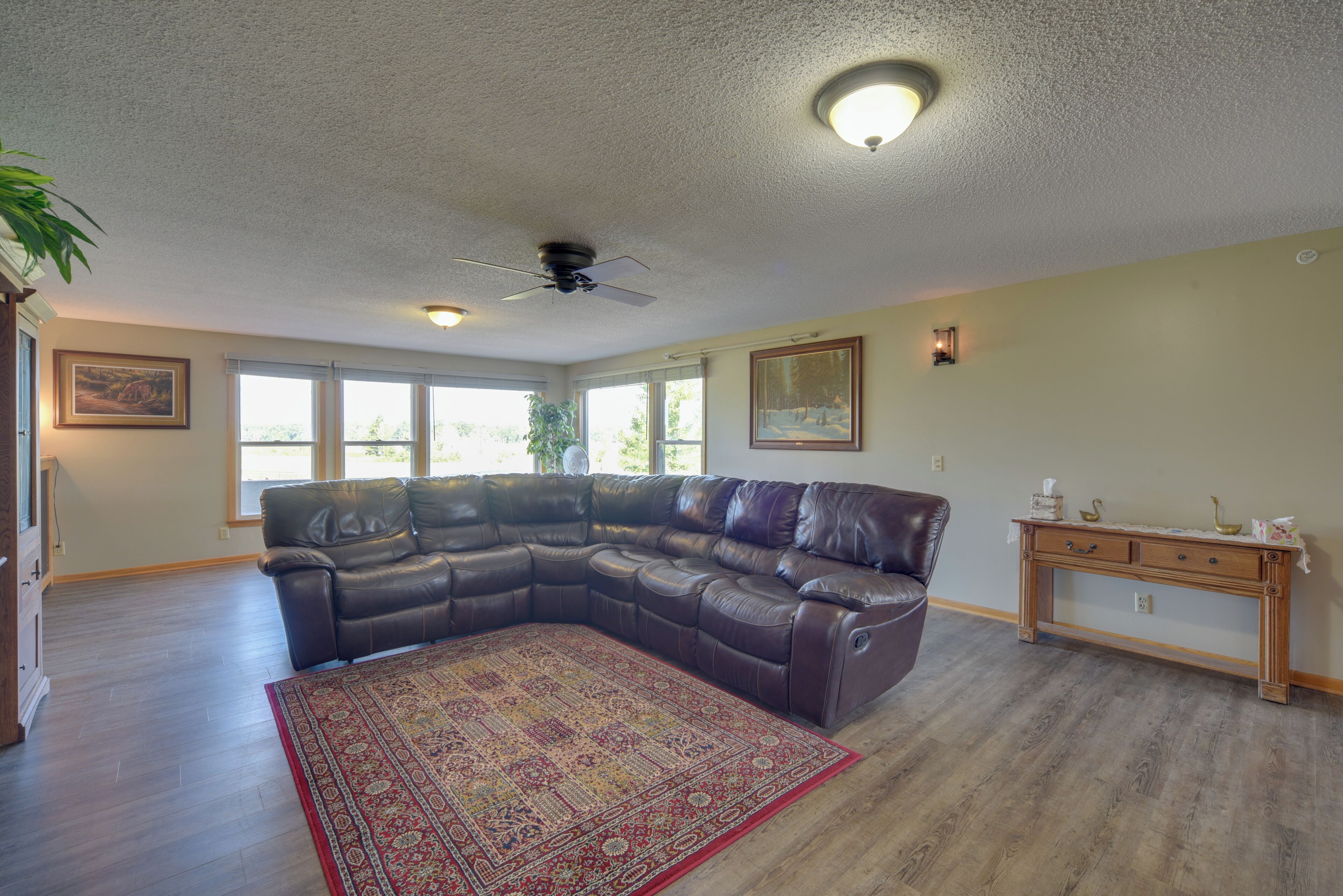 A spacious living room with a large sectional sofa, a wooden console table, and a patterned rug.