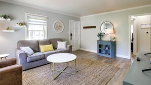 Un salon avec un canapé gris, une table basse ronde et un meuble bleu doté d’un miroir.