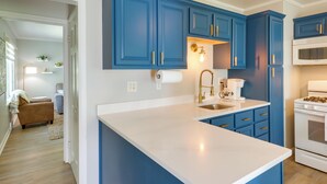 Une cuisine moderne avec des meubles bleus, un plan de travail blanc et un four encastré.