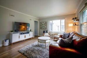 Una sala de estar con televisor, sofá y mesa de centro.