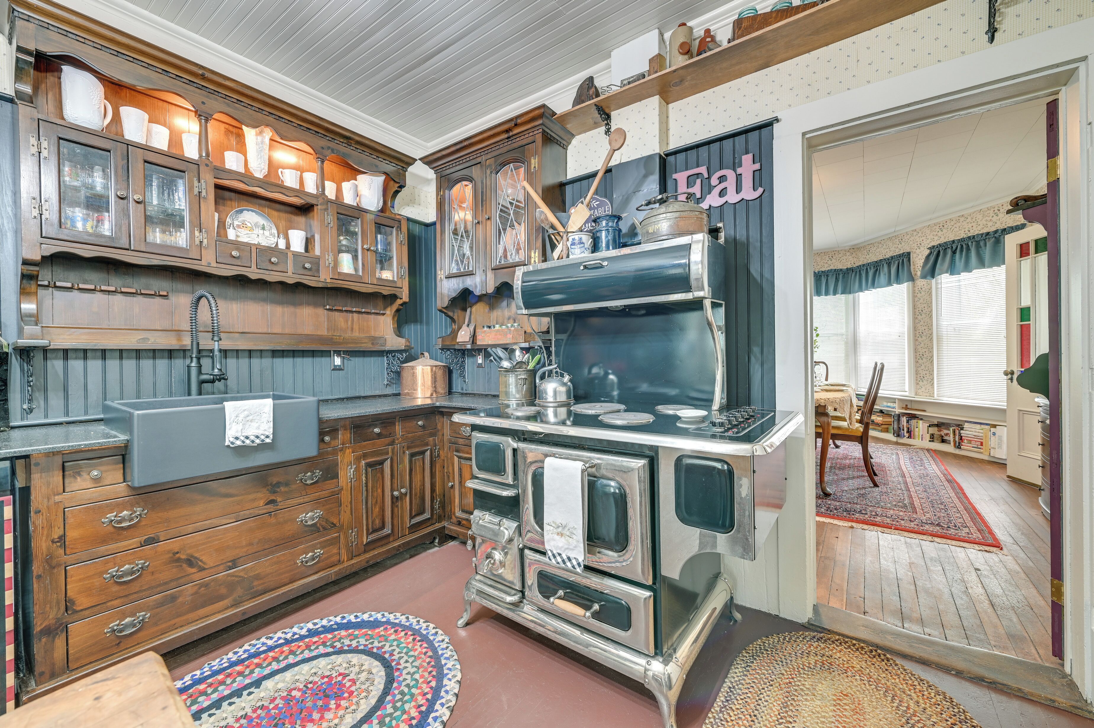A vintage kitchen with wooden cabinets, a sink, and a stove.