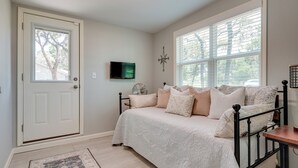 Ein Schlafzimmer mit Bett, Fernseher, einer Kompass-Wanddekoration und einem Fenster mit Jalousien.
