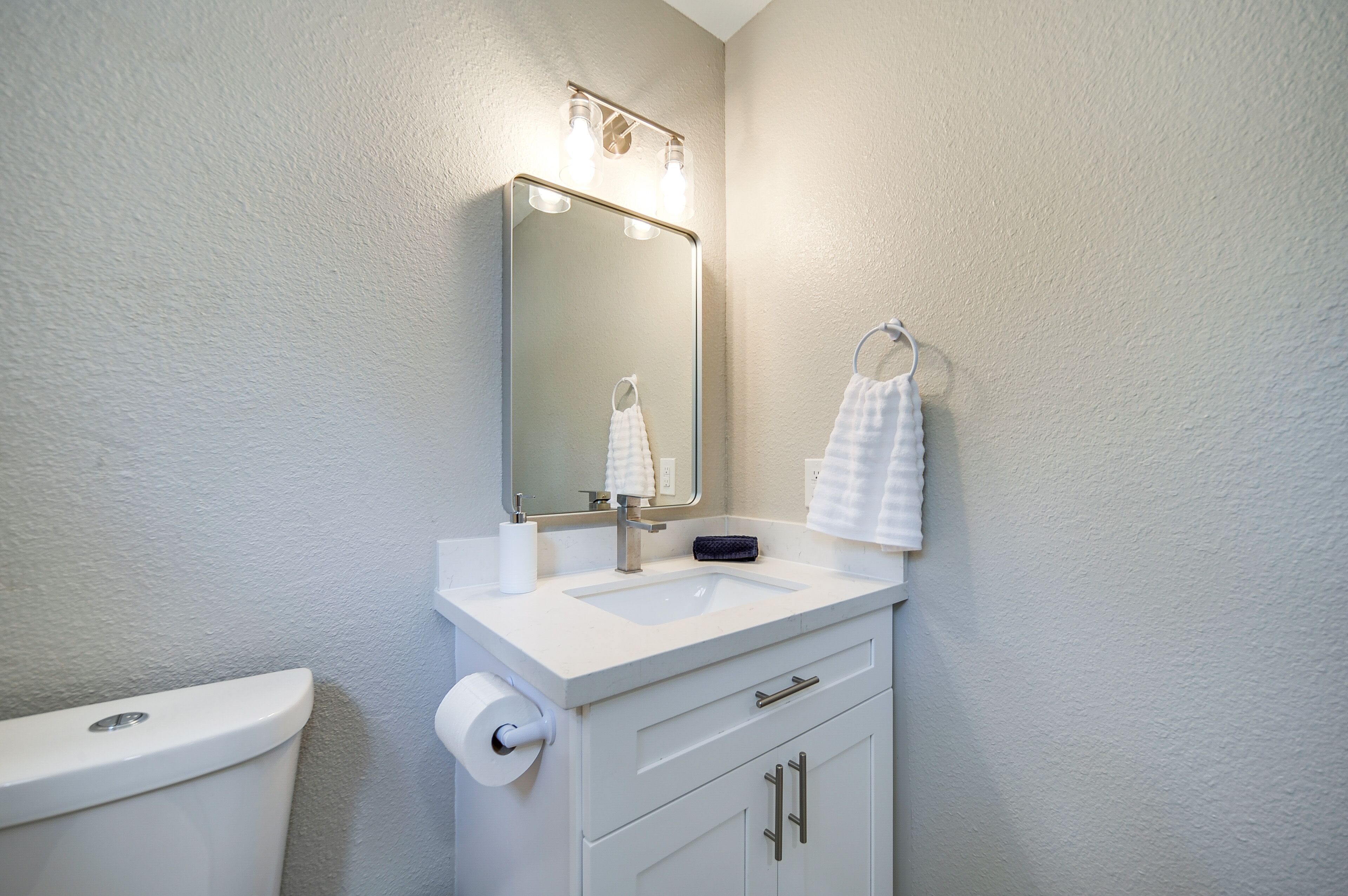 A bathroom with a white sink, mirror, and toilet.