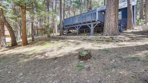 Una cabaña en un bosque con una terraza de madera y un muro de piedra.