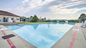 A swimming pool with clear blue water, a lifeguard stand, and a building with a green roof in the background. - 'sasquatch Inn' Albrightsville Cottage With Deck (Albrightsville)