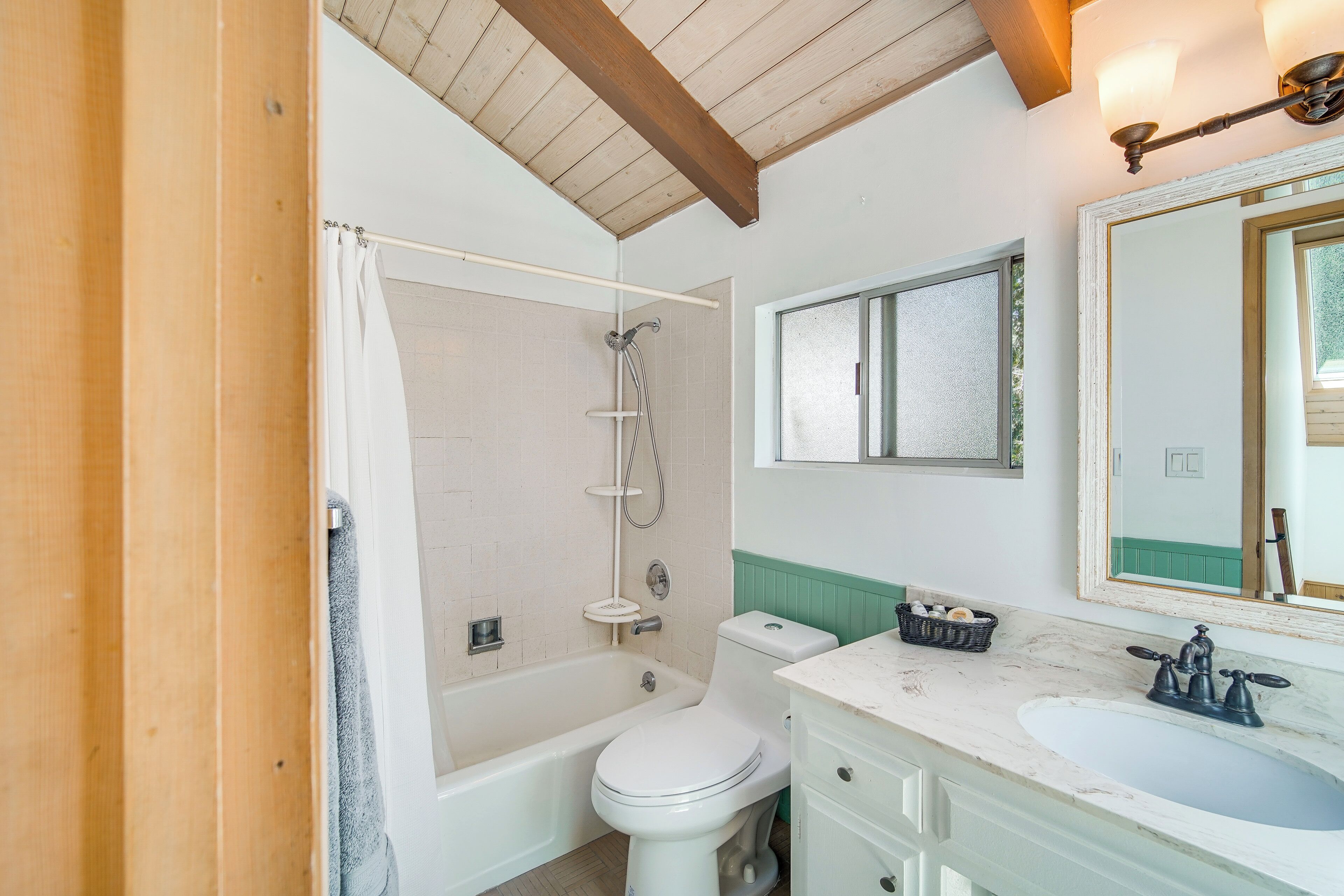 Un bagno con vasca, WC, lavandino e specchio.