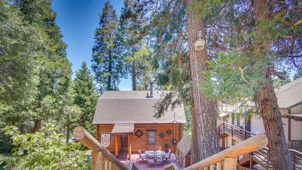 A wooden cabin with a porch, a dining area, and a staircase leading to a deck. - Crestline Area Vacation Rental Cabin w/ Decks! (Cedarpines Park)