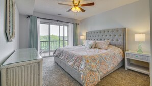 Une chambre avec un grand lit, un ventilateur de plafond, une table en verre et une vue sur l’extérieur.